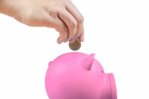 Make Extra Money: hand putting a coin in a piggy bank